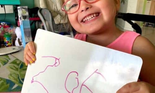 young girl holding up her drawing